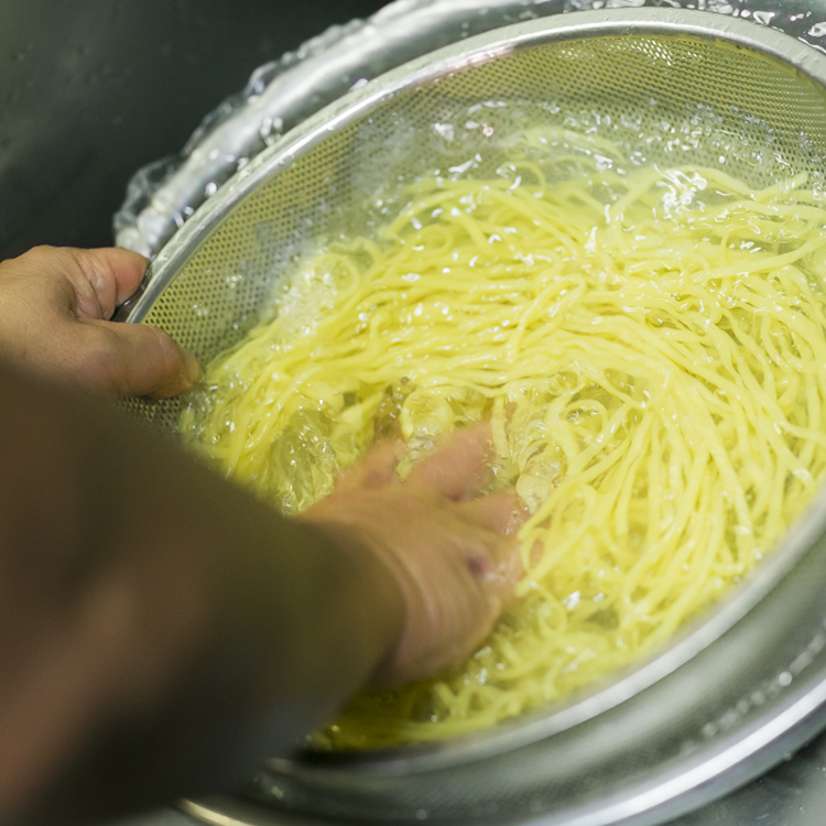 茹でた麺を冷水で勢い良く締める写真