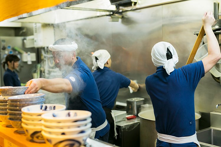 厨房でスタッフたちが真剣に仕事をしている様子の写真