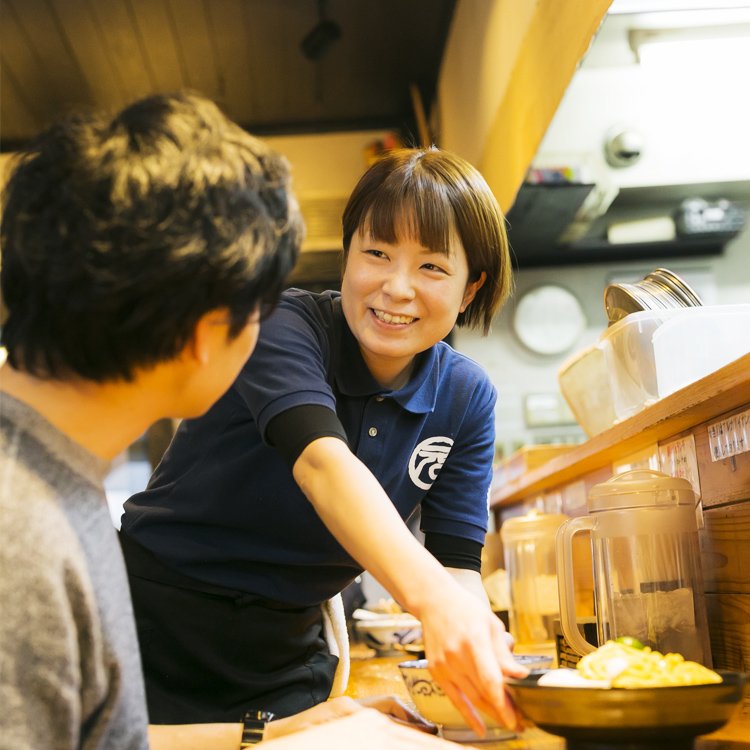 女性のスタッフが笑顔で接客している写真